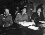 General Alfred Jodl (1890 - 1946) Hitler's military advisor, controller of German High Command and chief of the Operations Staff (centre), signs the document of surrender (German Capitulation) of the German armed forces at Reims in General Eisenhower's headquarters. He is joined by Major Wilhelm Oxenius (left) and Hans Georg von Friedeburg, Admiral of the Fleet (right). Original Publication: People Disc - HF0475 (Photo by Keystone/Getty Images)